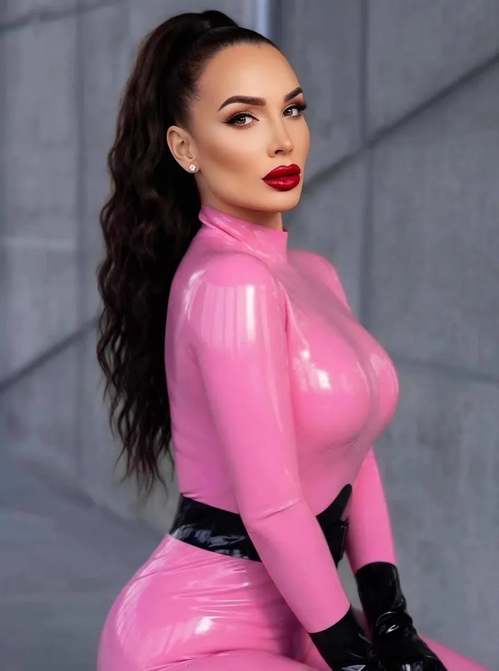 Halbporträt von Kara in einem rosa Latexoberteil vor grauem Hintergrund.